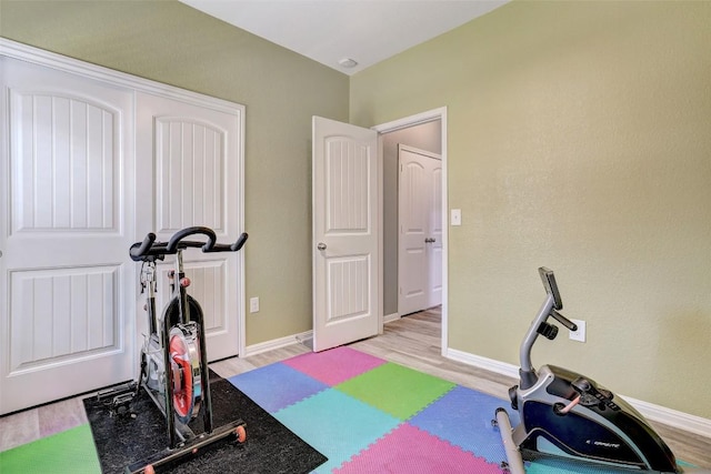 workout room featuring baseboards and light wood finished floors