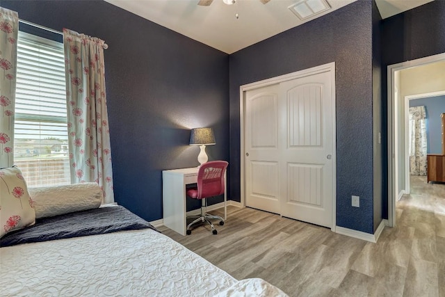 bedroom with baseboards, visible vents, wood finished floors, and a closet