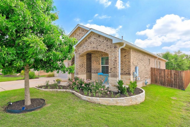 view of property exterior featuring a yard, brick siding, fence, and concrete driveway