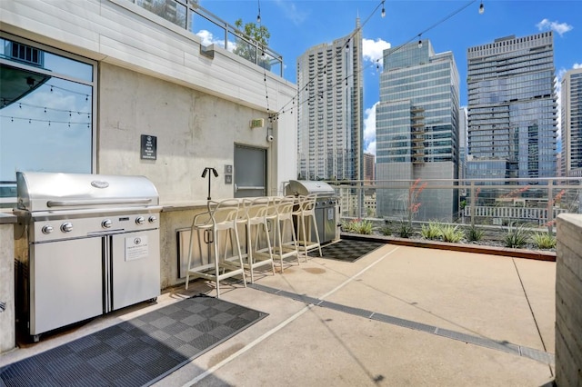 view of patio / terrace featuring a view of city, a bar, exterior kitchen, and grilling area