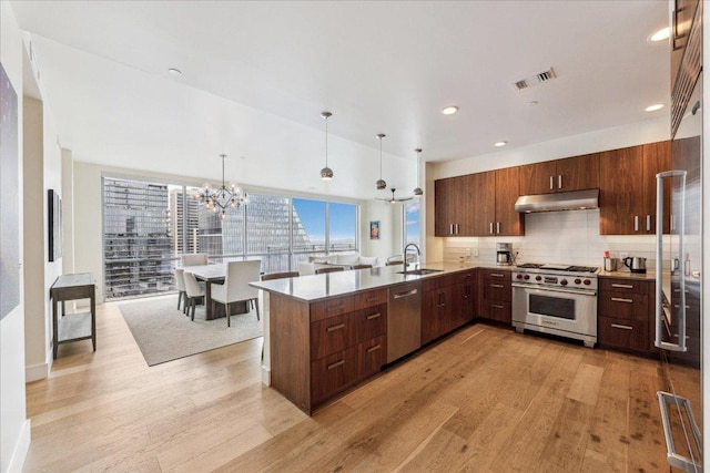 kitchen with visible vents, under cabinet range hood, a sink, light wood finished floors, and stainless steel appliances