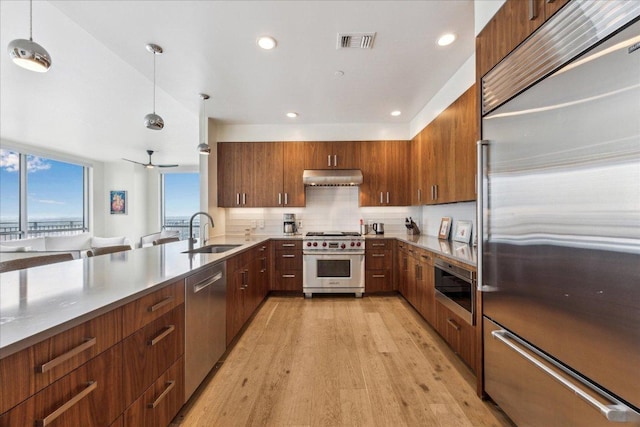 kitchen with visible vents, built in appliances, under cabinet range hood, a sink, and light wood-style flooring