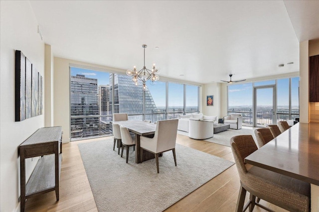 dining area with light wood-style floors, a view of city, expansive windows, and a chandelier