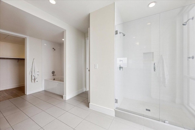 bathroom with a bathing tub, baseboards, a shower stall, and tile patterned floors