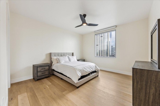 bedroom with baseboards, light wood finished floors, and ceiling fan