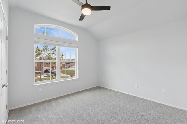 carpeted empty room featuring baseboards, ceiling fan, and vaulted ceiling
