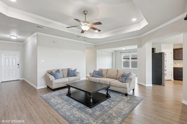 living room with a ceiling fan, baseboards, visible vents, and light wood finished floors