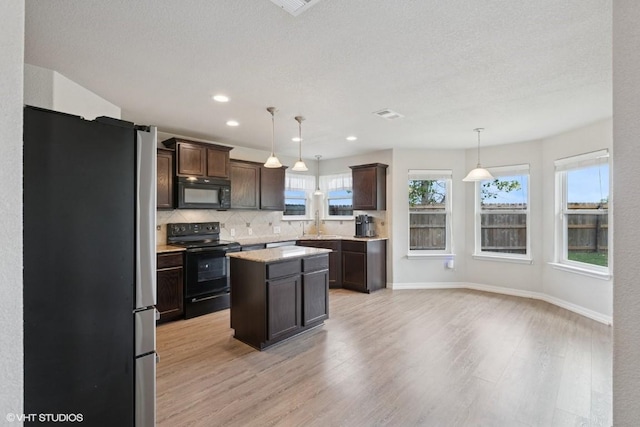 kitchen with light wood-style floors, dark brown cabinetry, black appliances, and backsplash