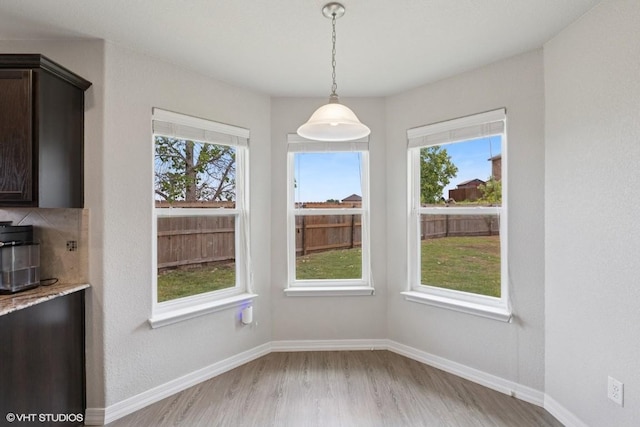 unfurnished dining area with baseboards, a healthy amount of sunlight, and light wood-type flooring