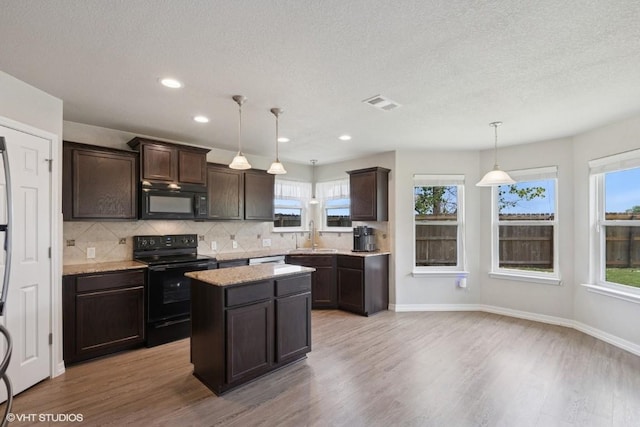 kitchen featuring visible vents, dark brown cabinetry, light wood-style floors, backsplash, and black appliances