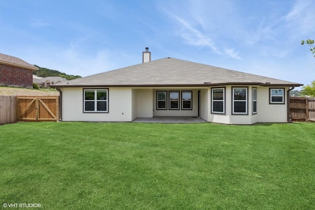 rear view of house with a yard, a patio, a chimney, and a fenced backyard