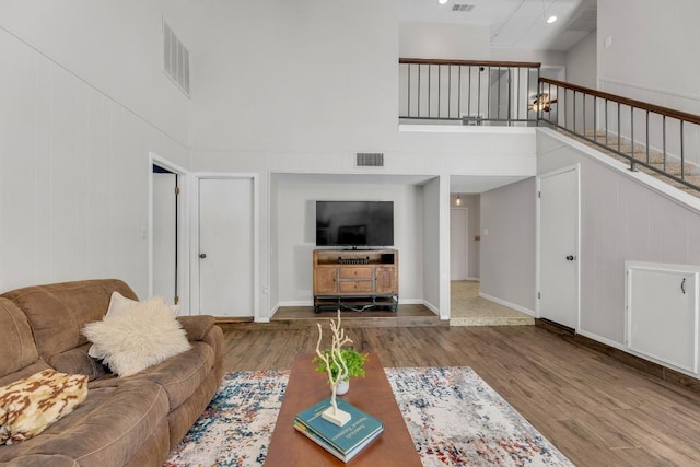living area with a high ceiling, visible vents, and wood finished floors