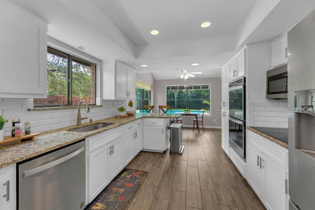 kitchen featuring a sink, white cabinetry, a peninsula, and stainless steel appliances