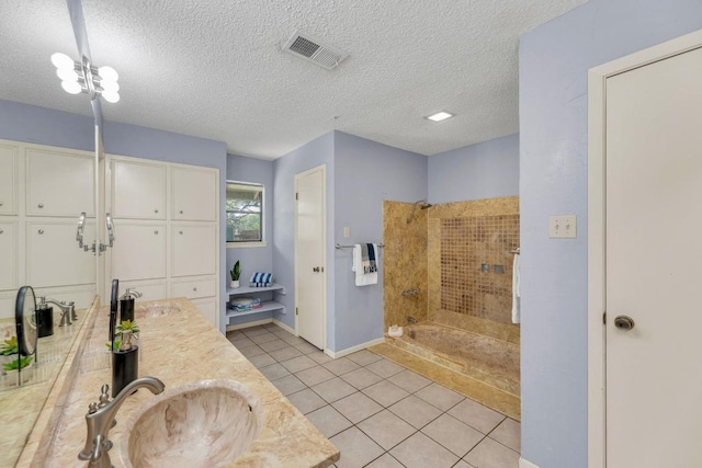 full bath featuring a textured ceiling, visible vents, tile patterned flooring, a tile shower, and a sink