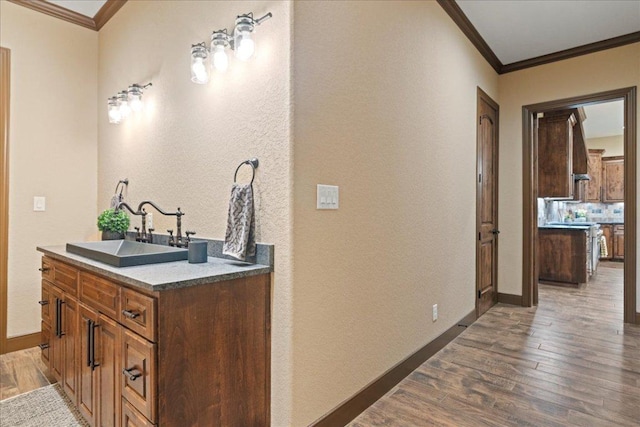 corridor with crown molding, dark wood finished floors, a sink, baseboards, and a textured wall