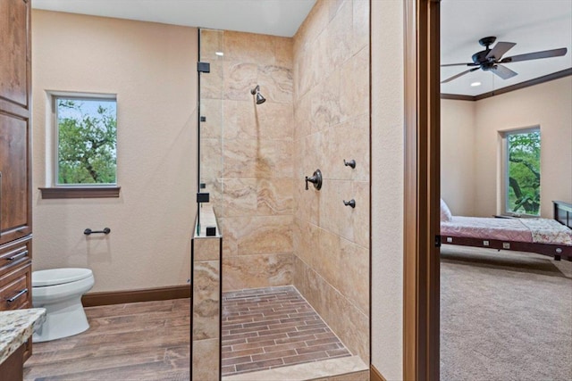 ensuite bathroom with ceiling fan, baseboards, toilet, ensuite bathroom, and tiled shower