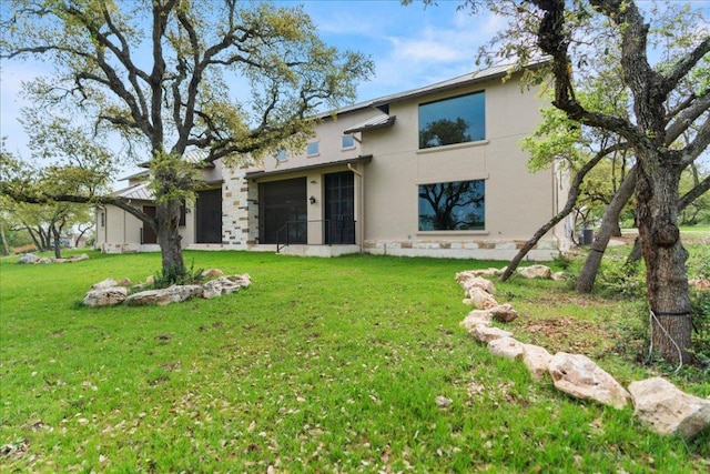rear view of house featuring a yard and stucco siding