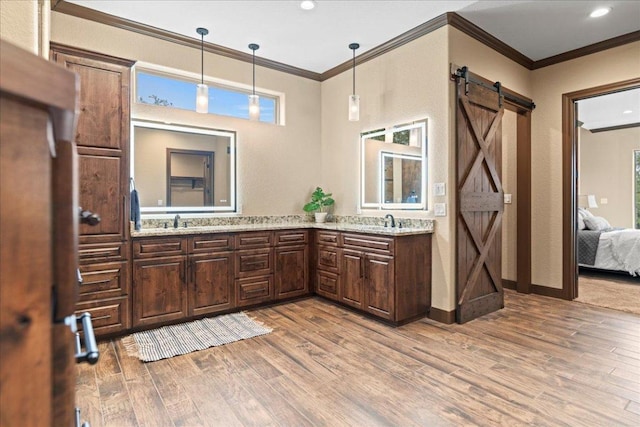bathroom featuring crown molding, double vanity, a sink, and wood finished floors