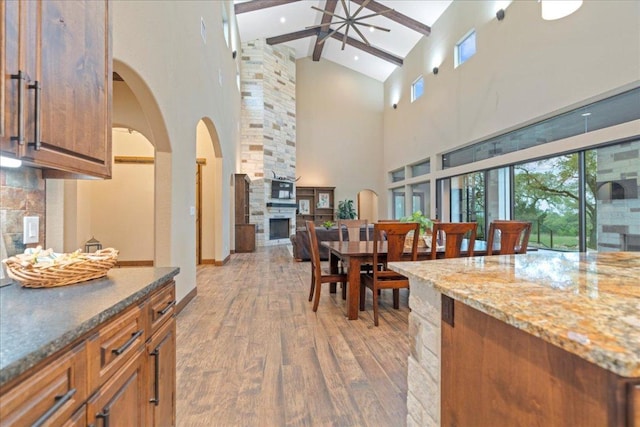 interior space featuring a ceiling fan, high vaulted ceiling, beam ceiling, and light wood-style floors