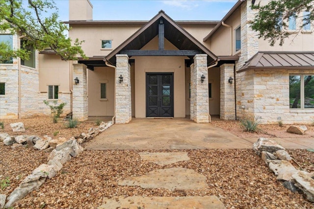 view of front of house featuring stone siding, stucco siding, a chimney, a standing seam roof, and metal roof