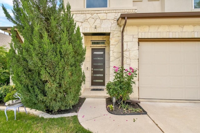 view of exterior entry featuring concrete driveway, stone siding, and stucco siding