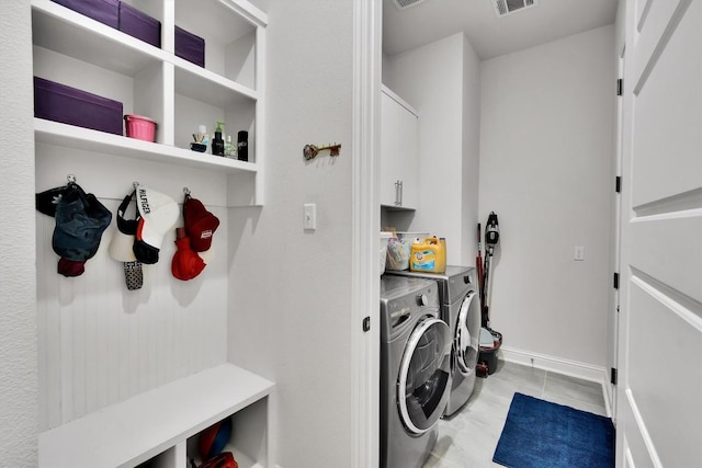 clothes washing area with visible vents, baseboards, washing machine and clothes dryer, cabinet space, and light tile patterned floors
