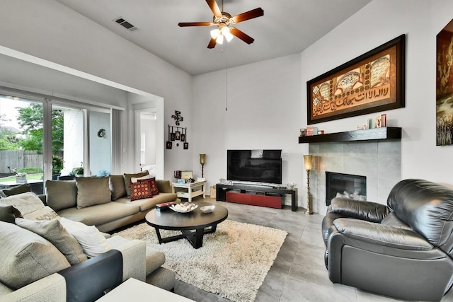 living area featuring a tiled fireplace, ceiling fan, and visible vents