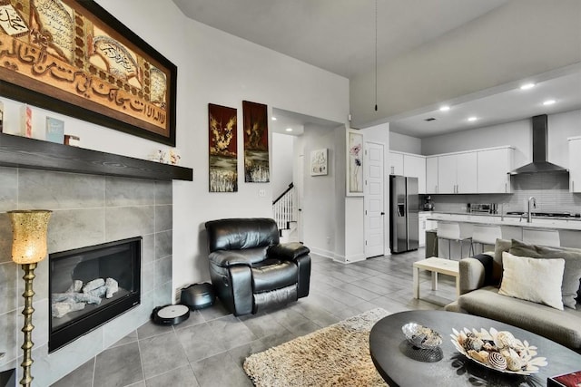 living room featuring stairway, baseboards, recessed lighting, and a tile fireplace
