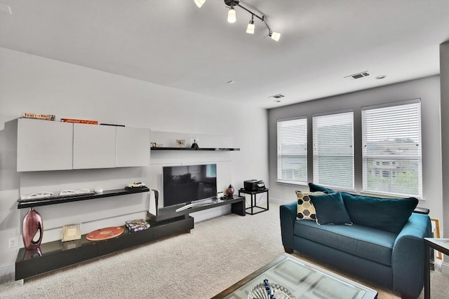 living area featuring rail lighting, visible vents, and light carpet