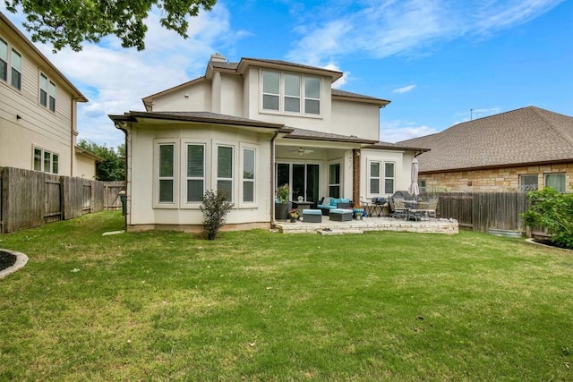 back of property with stucco siding, ceiling fan, a fenced backyard, an outdoor living space, and a lawn
