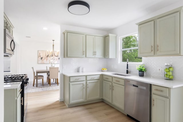 815 Sheraton Ave, Austin, TX 78745 - kitchen featuring appliances with stainless steel finishes, a sink, tasteful backsplash, light wood-style floors, and a chandelier