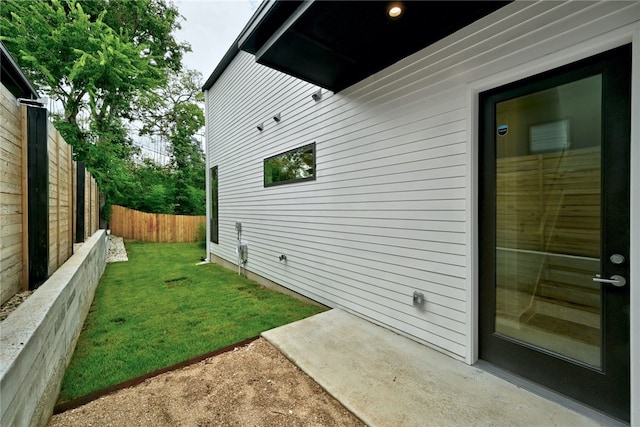 view of property exterior featuring a lawn, a patio, and fence