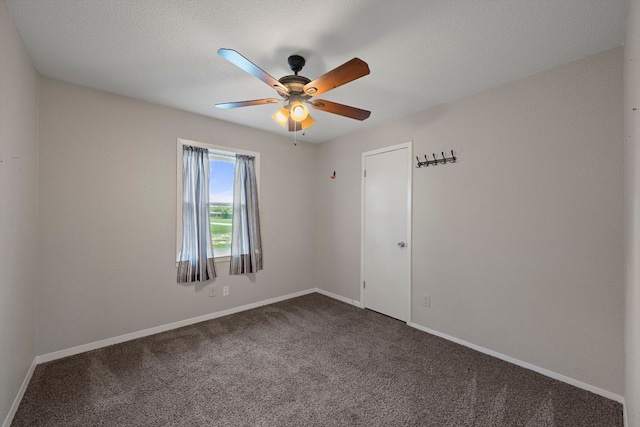empty room featuring baseboards, ceiling fan, and dark colored carpet