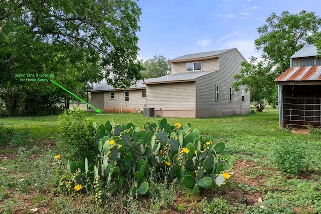 rear view of house with a lawn, central AC, and metal roof