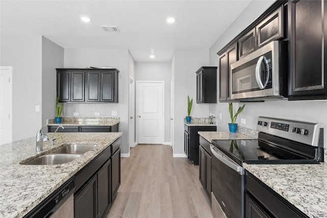 509 Peony Ct, Jarrell, TX 76537 - kitchen featuring light wood-style floors, a sink, appliances with stainless steel finishes, and light stone counters
