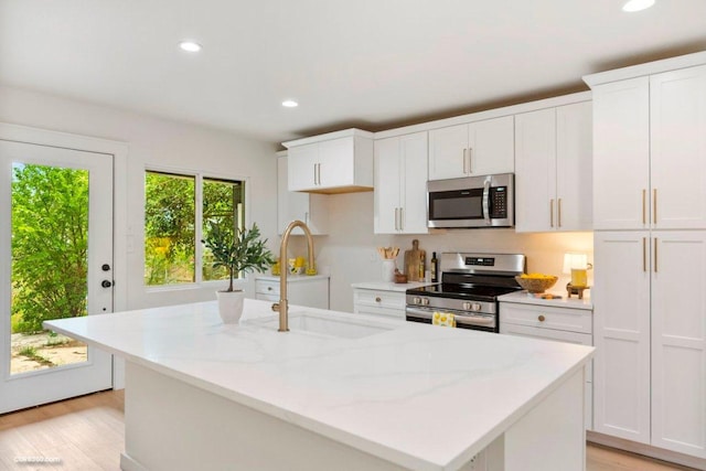 kitchen featuring a sink, light wood-style floors, stainless steel appliances, and white cabinetry