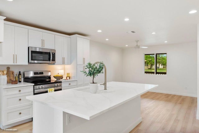 kitchen featuring appliances with stainless steel finishes, light wood finished floors, recessed lighting, and white cabinetry