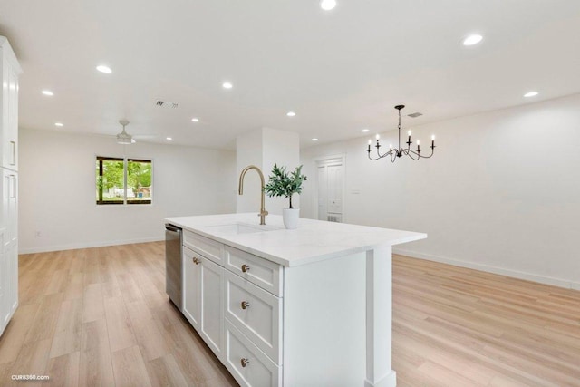 kitchen featuring light wood-style floors, a sink, dishwasher, and white cabinets