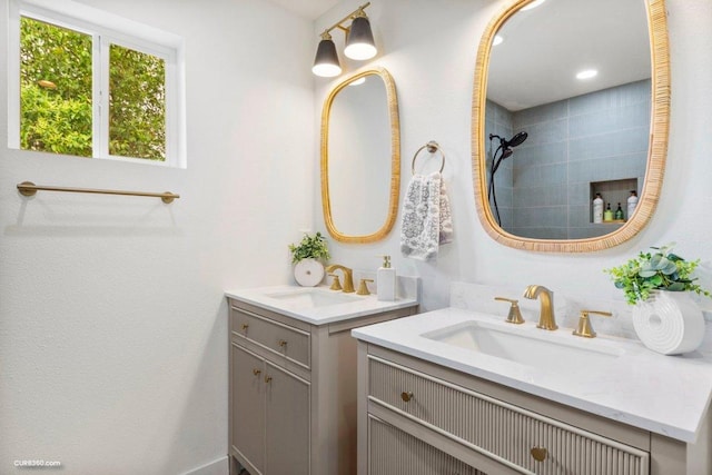 bathroom featuring a sink, two vanities, and tiled shower