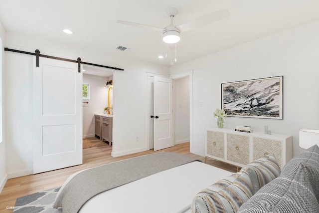 bedroom featuring recessed lighting, light wood-type flooring, a barn door, and visible vents