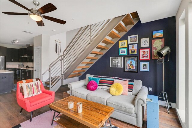 living area featuring visible vents, a ceiling fan, stairs, and wood finished floors