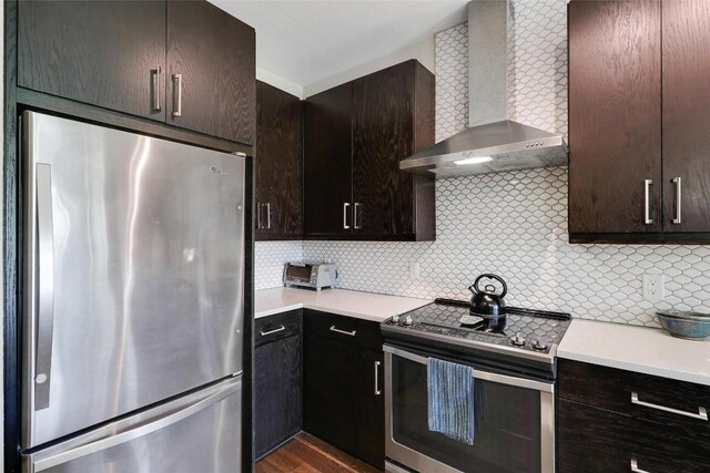 kitchen with wall chimney range hood, light countertops, backsplash, and stainless steel appliances
