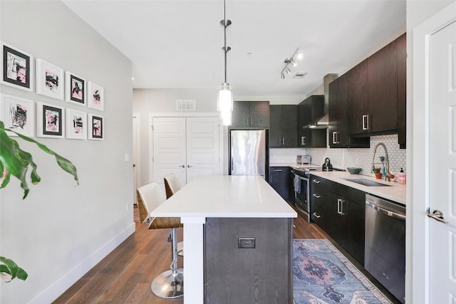 kitchen with baseboards, a kitchen breakfast bar, light countertops, a sink, and appliances with stainless steel finishes