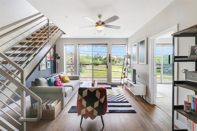 living area with a ceiling fan, a healthy amount of sunlight, hardwood / wood-style flooring, and stairway