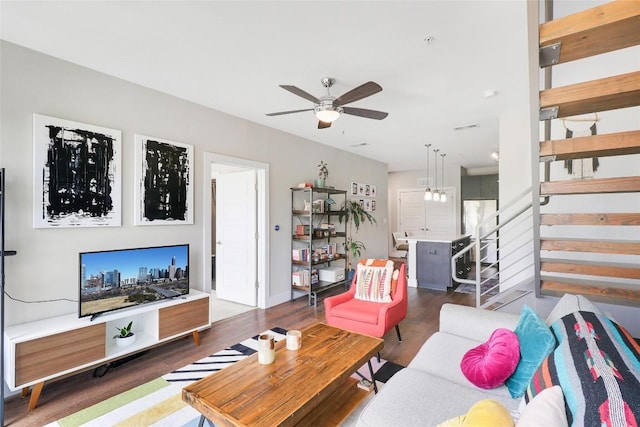 living area featuring visible vents, a ceiling fan, wood finished floors, and stairway