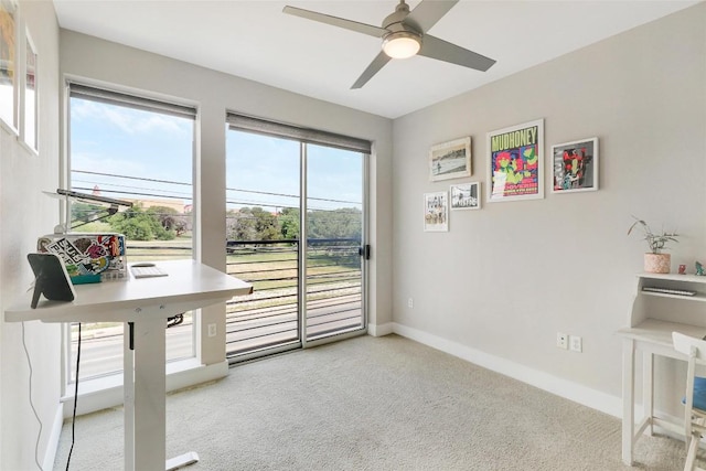 office space with baseboards, ceiling fan, and light carpet