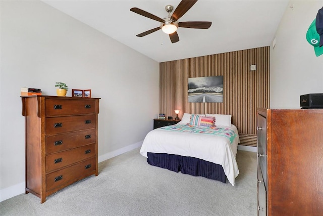 bedroom featuring baseboards, an accent wall, light carpet, and a ceiling fan