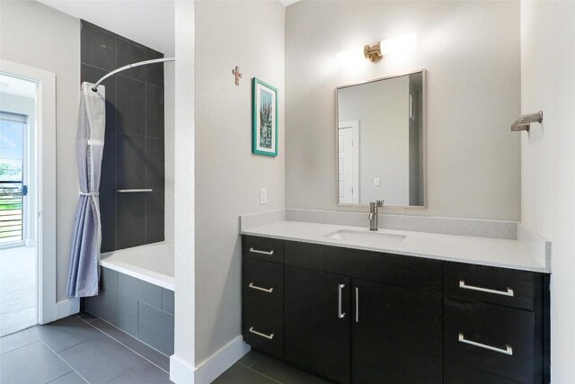 bathroom with tiled shower / bath, baseboards, tile patterned flooring, and vanity