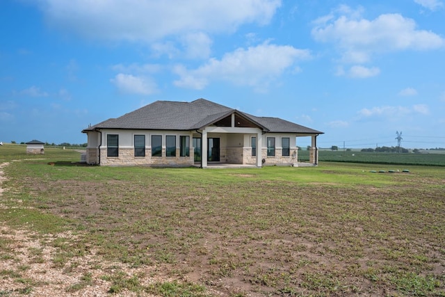 rear view of property featuring a lawn, a patio, stone siding, and stucco siding