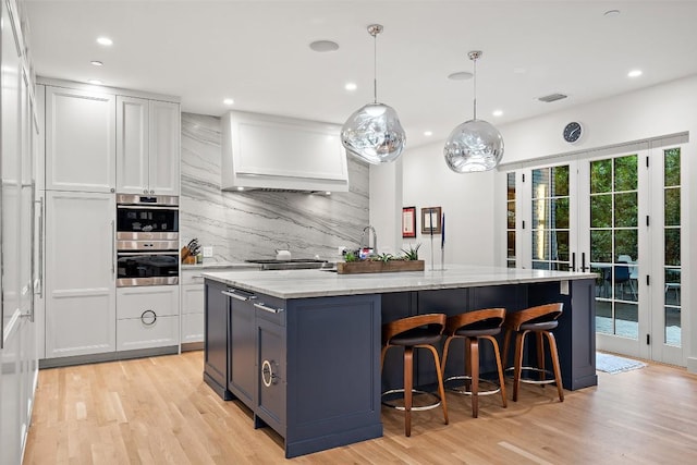 4203 Balcones Dr, Austin, TX 78731 - kitchen with backsplash, light stone counters, light wood-style flooring, a center island with sink, and recessed lighting